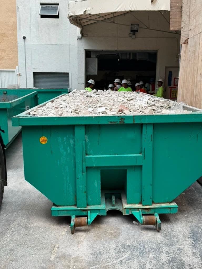 Dumpster filled with broken concrete and tile debris at a commercial site