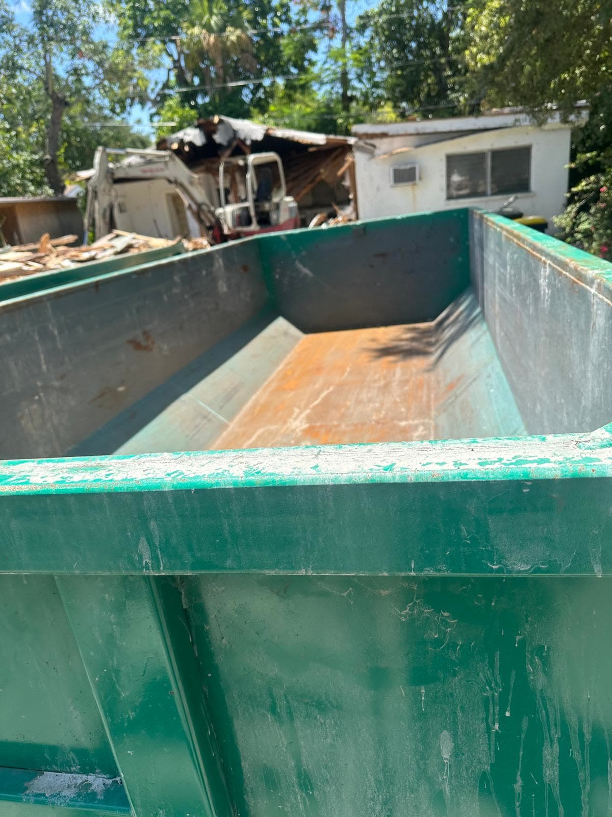Empty roll-off dumpster staged next to a demolition project